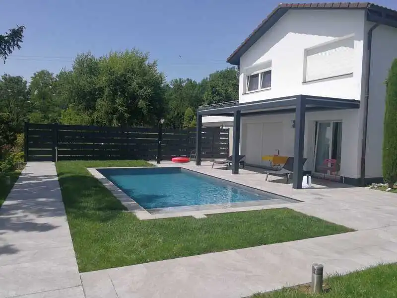 La clôture aluminium délimite l'espace piscine et sa pergola